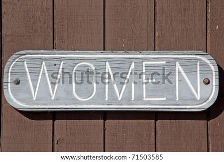 Photograph of a "women" sign on the outside of a park building.