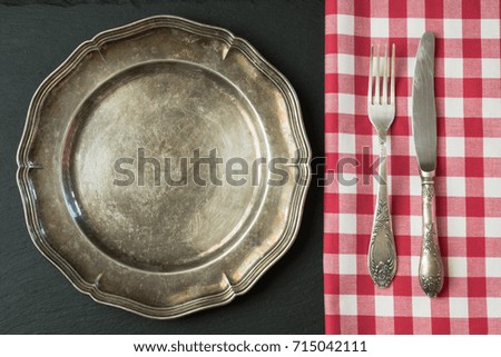 Empty metal dish with knife and fork on slate background, with copy space for your menu or recipe. Menu card for restaurants. Table place setting.