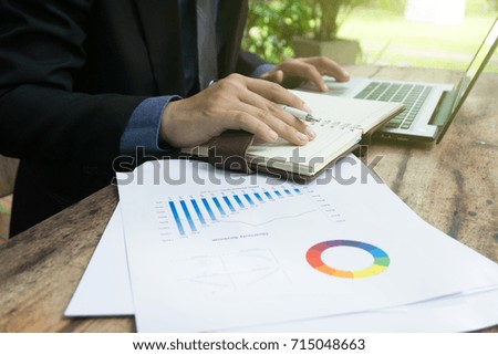 side view of businessmen using laptop analyzing marketing strategy with statistic graph and notebook on wooden desk.stock trading analysis.