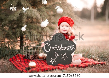 Cute kid girl 3-4 year old with christmas decorations outdoors. Looking at camera. Holiday season. Childhood. 