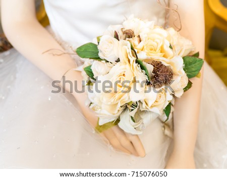 Hands of wedding bride dolls. Closeup of bride doll holding beautiful wedding bouquet flower with white bridal gown background. - Selective focus.