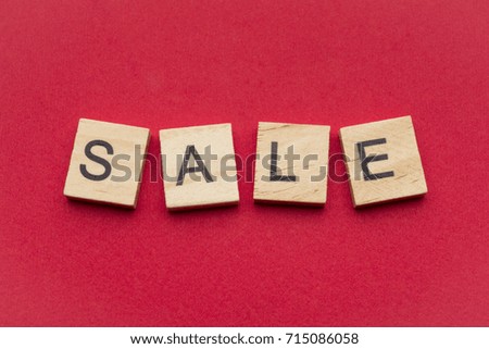 Sale word on wooden tiles isolated on red background