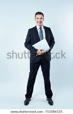Successful businessman posing with laptop over background