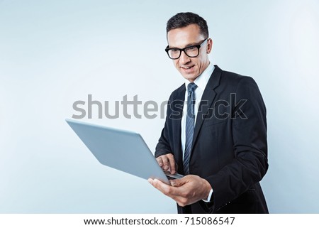 Interested mature man in suit looking at laptop