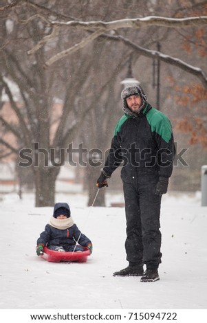Father pulls a child on a sled. Father and son sledding at winter time.
