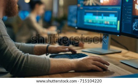 Male Videographer Edits and Cuts Footage and Sound on His Personal Computer with Two Displays. His Office is Modern and Creative Loft Studio.
