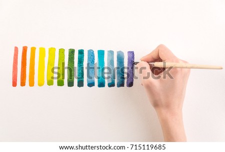 Artist painting colorful gradient stripes with watercolor paint and brush on white paper