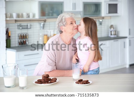 Cute little girl and her grandmother with cookies on kitchen