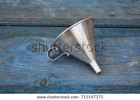 Vintage metal funnel with handle on old wooden blue garden table background Royalty-Free Stock Photo #715147375