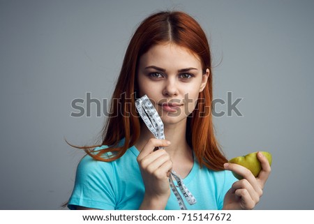  woman young with apple and measuring tape on gray background portrait, vitamins, healthy food, diet                              