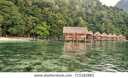 Bamboo hut house lined up along a beach, ora eco resort, maluku, indonesia