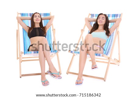 Beautiful young women sitting on deck chairs against white background