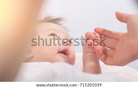 Asian New born girl smiling and playing with her mother. Baby holding mother finger. Royalty-Free Stock Photo #715201039
