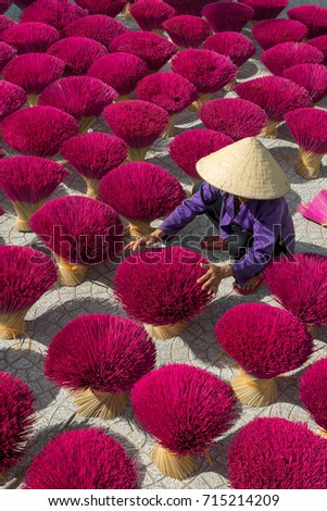 Woman wearning conical hat is drying sticks of incense at yard at Tay Ninh province, Vietnam