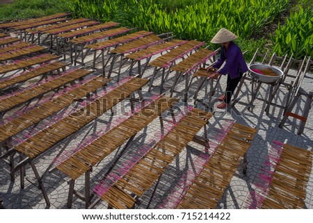 Woman wearning conical hat is drying sticks of incense at yard at Tay Ninh province, Vietnam