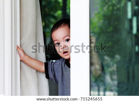 Toddler Asian boy open the sliding door that was unlocked.Boy open and try to get out from the house..Kid during Covid-19 locked down or self isolated,Self quarantine.Common danger hazard for kids. 