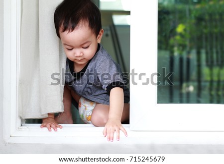 Toddler Asian boy open the sliding door that was unlocked.Boy open and try to get out from the house.Kid during Covid-19 locked down or self isolated,Self quarantine or Common danger hazard for kids.
