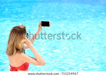 Beautiful young woman taking selfie near swimming pool