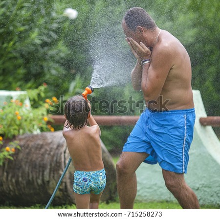 Father and son play on the garden with the water