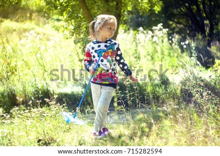 little girl in the beautiful park, with a net catches butterflies, smiles and laughs, playful mood, childish pranks