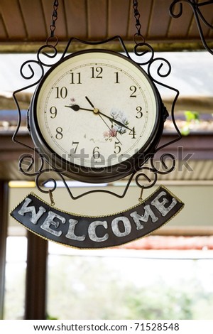 clock hanging with the word welcome.