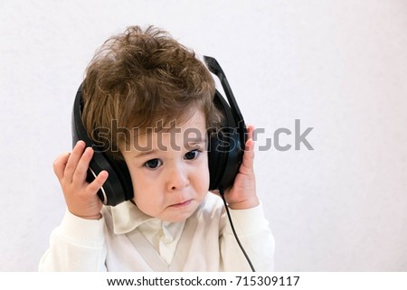 Pop music. Happy smiling newborn baby listens to music in headphones on gray background. Cheerful children's portrait. Little Adorable baby boy with big headphones. funny 
