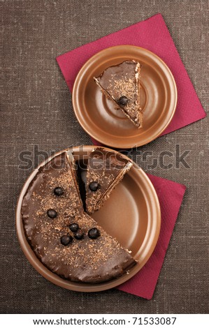 Two plates with homemade chocolate cake on brown canvas.