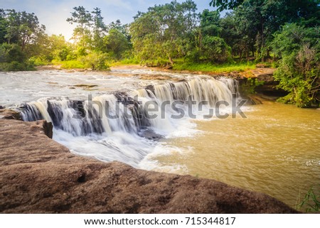 Exotic small waterfall for swimming named "Tadton Waterfall" in Ubon Ratchathani, Thailand. This cascade falls from a rocky bend like a movie screen through the large rock with large water flow.