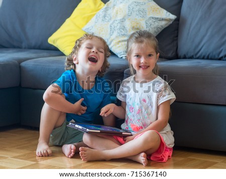 Brother and sister play games on the tablet, watch cartoons and laugh