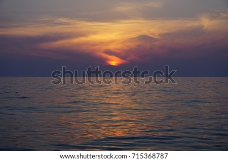 Calming images. Colorful sky with yellow red sun, orange blue clouds above Black sea evening today. Beautiful time after sunset. Lubimovka, Sevastopol, Crimea, Russia. Sunny light reflected on water