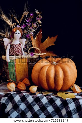 orange pumpkin  on a wooden table with decorations of autumn flowers  on the wooden table with checkered tablecloth.