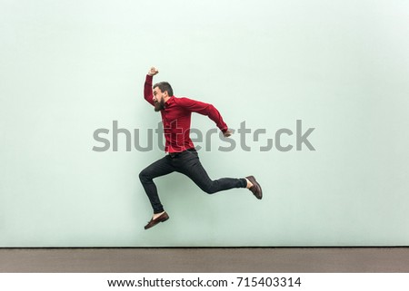 Was late for work in firs day. Young adult bearded man running to the work. Outdoor, gray wall
