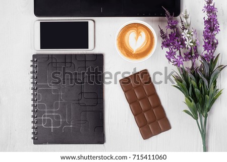 Cup of coffee cappuccino laptop flowers chocolate candy notebook mobile phone smartphone on a white wooden background Isolation