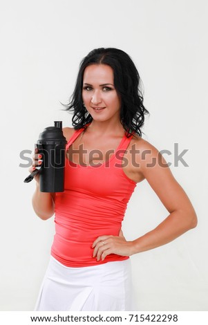 Young woman with protein shake bottle on white background