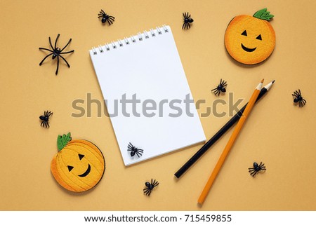 Empty open notepad  with Halloween decorations on orange backdrop. Festive  concept. Blank  space for text.