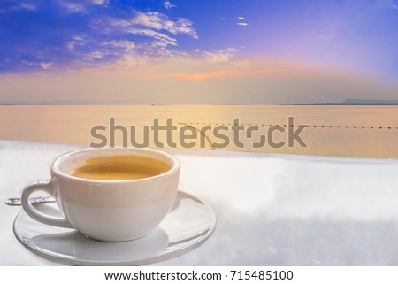 Cup of coffee with silhouette the sunset , the buoy, the swamp, the beautiful sky and cloud by the beam light ,shadow,lens flare effect tone background.