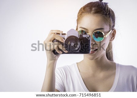 The photographer hipsters girl asian wear the white T-shirt and sunglasses coated mercury. She hold the camera in hand isolated on a white background.