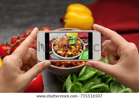 Woman taking photo of yummy stew at kitchen table