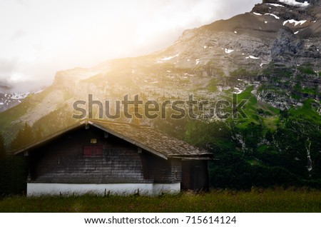 Alone house in the woods with big mountain and cloudy sky background in the evening at switzerland. Scary, horror and halloween day concept.
