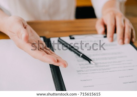 Close-up Of Businessperson with Signing Contract, man with contract paper at the desk with pen and reading books at table with basic business Form document working in office
