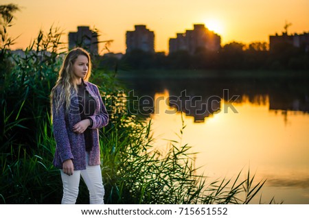 The girl is standing on the lake, at sunset