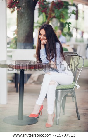 girl in white shirt and red shoes in the street sitting at the table, smile, fashion dressed