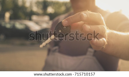 Senior man holding key car. Focus of hand.