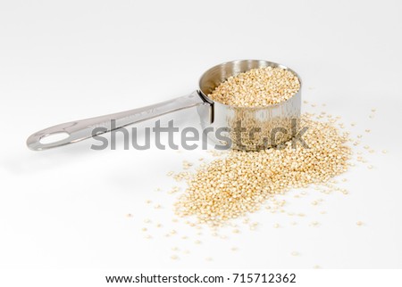 Spilled pile of uncooked quinoa with metal measuring cup Royalty-Free Stock Photo #715712362