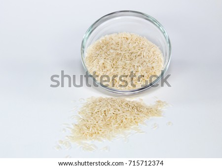 Uncooked basmati rice spilling out of a glass bowl Royalty-Free Stock Photo #715712374