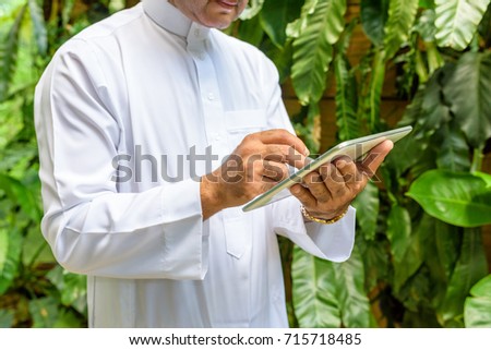 Arab muslim business man ware white traditional clothing in hand writing something on digital tablet