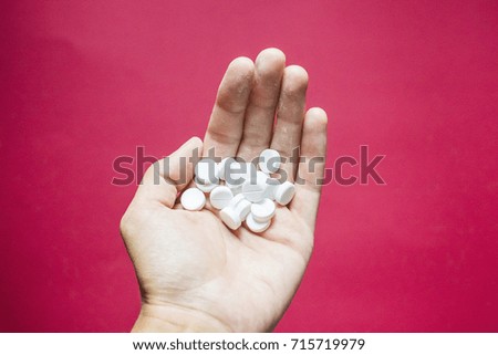 White pills in the hand on pink background