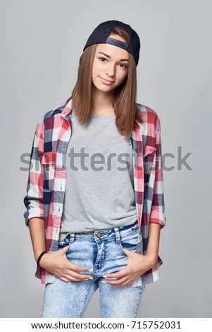 Teen girl standing relaxed with hands in pockets over grey background