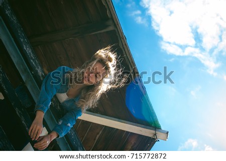 young beautiful woman in jeans clothes outdoors. portrait of a girl with freckles on her face, stylish girl on sea beach rescue tower, on a sunny summer autumn day. happy pulls hands to hug