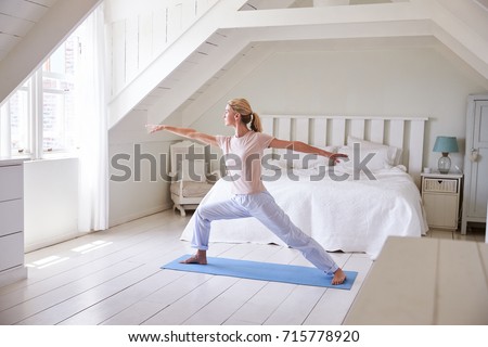 Woman At Home Starting Morning With Yoga Exercises In Bedroom Royalty-Free Stock Photo #715778920